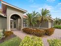 Front entry with arched doorway, brick walkway, and lush landscaping at 4472 Via Del Villetti Dr, Venice, FL 34293