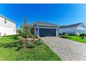 Gray house with paver driveway and nicely landscaped yard at 4514 Big Woods Way, Parrish, FL 34219