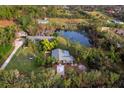 Aerial view of secluded property with pond and two residences, surrounded by green landscape at 5645 Churchill Downs Rd, Sarasota, FL 34241