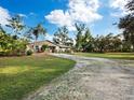 Ranch-style home with a large grassy yard and gravel driveway at 5645 Churchill Downs Rd, Sarasota, FL 34241