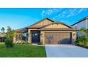 House exterior showcasing a stone accent, landscaping, and a modern garage door at 6138 162Nd E Ave, Parrish, FL 34219