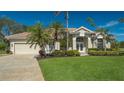 Tan house with lush landscaping and a three-car garage at 770 Egret Walk Ln, Venice, FL 34292