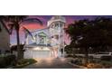Three-story pastel home with a wrap-around porch and palm trees in the foreground at 112 Mangrove Ave, Anna Maria, FL 34216