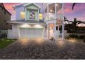 Pastel-colored three-story house with a two-car garage and brick driveway at 112 Mangrove Ave, Anna Maria, FL 34216