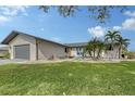 Single-story home with gray siding, attached garage, and landscaped lawn at 128 Sinclair Se St, Port Charlotte, FL 33952