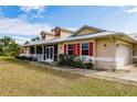 Tan house with red shutters, screened porch, and metal roof at 27425 Jones Loop Rd, Punta Gorda, FL 33982