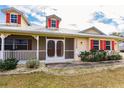 Front porch with red door, white railings and landscaping at 27425 Jones Loop Rd, Punta Gorda, FL 33982