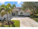 Front view of a house with palm trees, a three-car garage and a large driveway at 4214 Palacio Dr, Sarasota, FL 34238