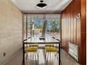 Dining room with a modern table, yellow chairs, wood-paneled walls, and bright light from the window at 1695 Lowe Dr, Sarasota, FL 34236
