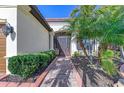 Front entry with a brick walkway, lush landscaping, and a decorative door at 20107 Uffizi Ct, Venice, FL 34293