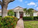 Brick paver walkway leading to a home with a red door and manicured landscaping at 7207 Saint Johns Way, University Park, FL 34201