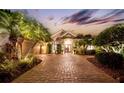 Elegant home with brick paver driveway and palm trees at dusk at 11432 Savannah Lakes Dr, Parrish, FL 34219