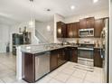 Modern kitchen featuring dark cabinetry, granite counters, and stainless steel appliances at 14339 Easy Goer St, Ruskin, FL 33573
