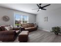 Living room with brown leather furniture, ceiling fan, and large window at 15404 Trinity Fall Way, Bradenton, FL 34212