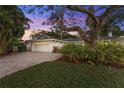 White home with large tree and paver driveway at dusk at 4810 Bay Shore Rd, Sarasota, FL 34234