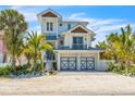 Two-story house with light blue metal roof, two-car garage, and palm trees at 518 Spring Ave, Anna Maria, FL 34216