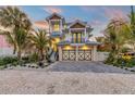 Two-story house with light blue metal roof, two-car garage, and palm trees at 518 Spring Ave, Anna Maria, FL 34216