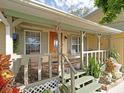 Inviting front porch with a wooden door, lovely decorations, seating and view to the front yard at 5411 9Th E St, Bradenton, FL 34203