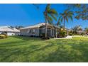 Landscaped yard with a teal single story house and palm trees at 7203 41St E Ct, Sarasota, FL 34243