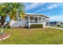 Landscaped manufactured home with covered porch and palm tree at 1108 43Rd Avenue E Dr, Ellenton, FL 34222