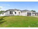 White house with gray roof and dark gray garage door, nicely landscaped lawn at 5595 Delight Ave, North Port, FL 34288