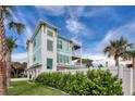 Side view of a teal home with a lush green hedge and palm trees at 630 Companion Way, Longboat Key, FL 34228