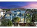 Two-story home with blue siding, metal roof, and palm trees at dusk at 307 Compass Point Dr # 101, Bradenton, FL 34209