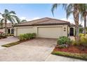 Two-car garage, light beige exterior, and landscaped yard at 20289 Benissimo Dr, Venice, FL 34293