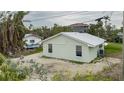 Light green house with metal roof, gravel driveway, and mature landscaping at 29 Mound, Terra Ceia, FL 34250