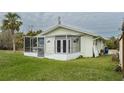 Back of house featuring a screened porch and grassy yard at 29 Mound, Terra Ceia, FL 34250