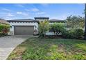 House exterior with gray garage door and lush landscaping at 328 Aria Dr, Nokomis, FL 34275