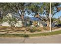 Exterior view of a light green house with a metal roof, landscaping, and a large tree at 510 45Th E St, Bradenton, FL 34208