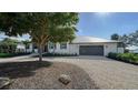 White, single-story home with a gray garage and mature landscaping at 7820 Holiday Dr, Sarasota, FL 34231