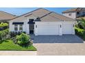 White two-story house with a two-car garage and paver driveway at 7917 Mainsail Ln, Sarasota, FL 34240