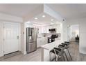 Modern white kitchen with stainless steel appliances and breakfast bar at 3751 S School Ave # 11, Sarasota, FL 34239