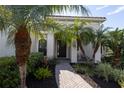 Inviting front entry with a brick walkway, lush landscaping, and a charming covered porch at 7817 Passionflower Dr, Sarasota, FL 34241