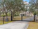Entrance with black metal gate and wood fencing at 8107 High Oaks Trl, Myakka City, FL 34251