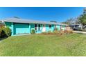 Newly renovated teal home with gray metal roof and white garage door at 511 E 65Th Ave, Bradenton, FL 34203