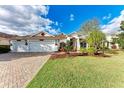 House exterior featuring a three-car garage, landscaped yard, and brick paver driveway at 12031 Longview Lake Cir, Bradenton, FL 34211