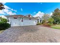 Three-car garage with decorative paver driveway and lush landscaping at 12031 Longview Lake Cir, Bradenton, FL 34211