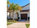 White house with brown garage door, palm trees, and landscaped lawn at 17322 Holly Well Ave, Wimauma, FL 33598