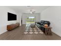 Living room with hardwood floors, a black leather sofa, and sliding glass doors at 17322 Holly Well Ave, Wimauma, FL 33598