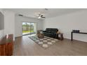 Living room with hardwood floors, a black leather sofa, and sliding glass doors at 17322 Holly Well Ave, Wimauma, FL 33598