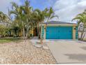 Yellow house with teal garage door and tropical landscaping at 3972 Titan St, North Port, FL 34286