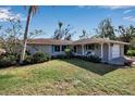 Ranch-style home with a spacious lawn, palm trees, and attached garage at 5708 Miami Rd, Venice, FL 34293