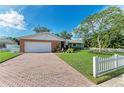 Brick ranch house with a white garage door, lush lawn, and brick paver driveway at 710 44Th W St, Bradenton, FL 34209