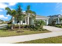 House exterior showcasing a light gray color, landscaping, and paver driveway at 8725 Sundance Loop, Sarasota, FL 34238