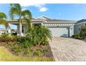 Light gray house exterior with landscaping, paver driveway, and tropical plants at 8725 Sundance Loop, Sarasota, FL 34238