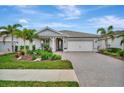 Well-maintained house featuring a paver driveway and lush landscaping at 26017 Seastone Dr, Englewood, FL 34223