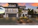 Modern three-story home with a large driveway and palm trees at 6605 Gulf Dr, Holmes Beach, FL 34217